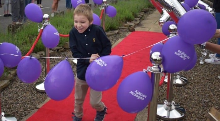A child walking on a carpet with epilepsy society balloons